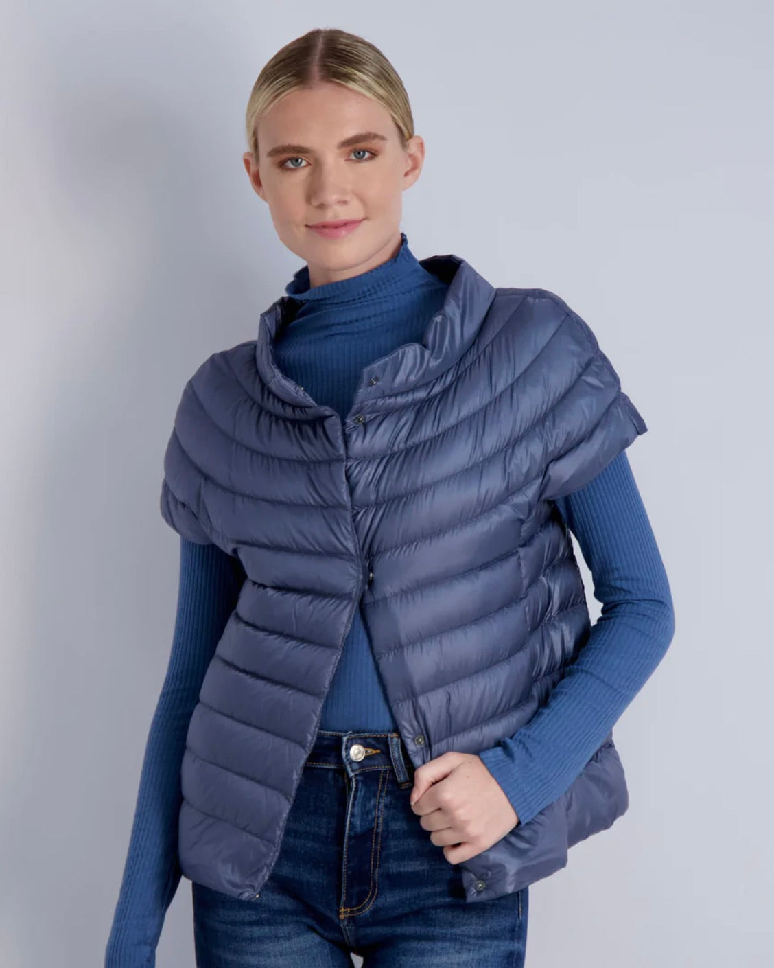 Model wearing Cotes of London St Barts Down Vest wearing jeans and a blue turtleneck on a white background 