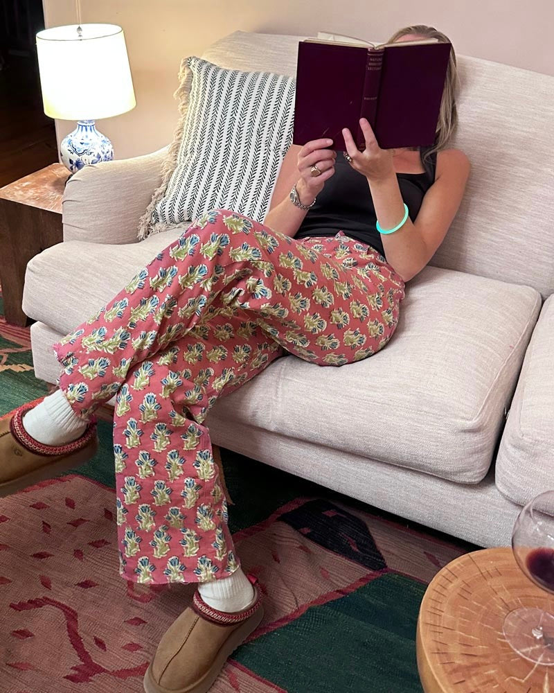 Model wearing Emerson Fry India Collection Everyday Pant Bell Flower Twill Organic wearing Ugg Slippers drinking wine reading a book sitting on a couch