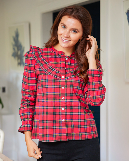 Model wearing Sail to Sable Cotton red tartan ruffle neck top wearing black pants standing in front of a door