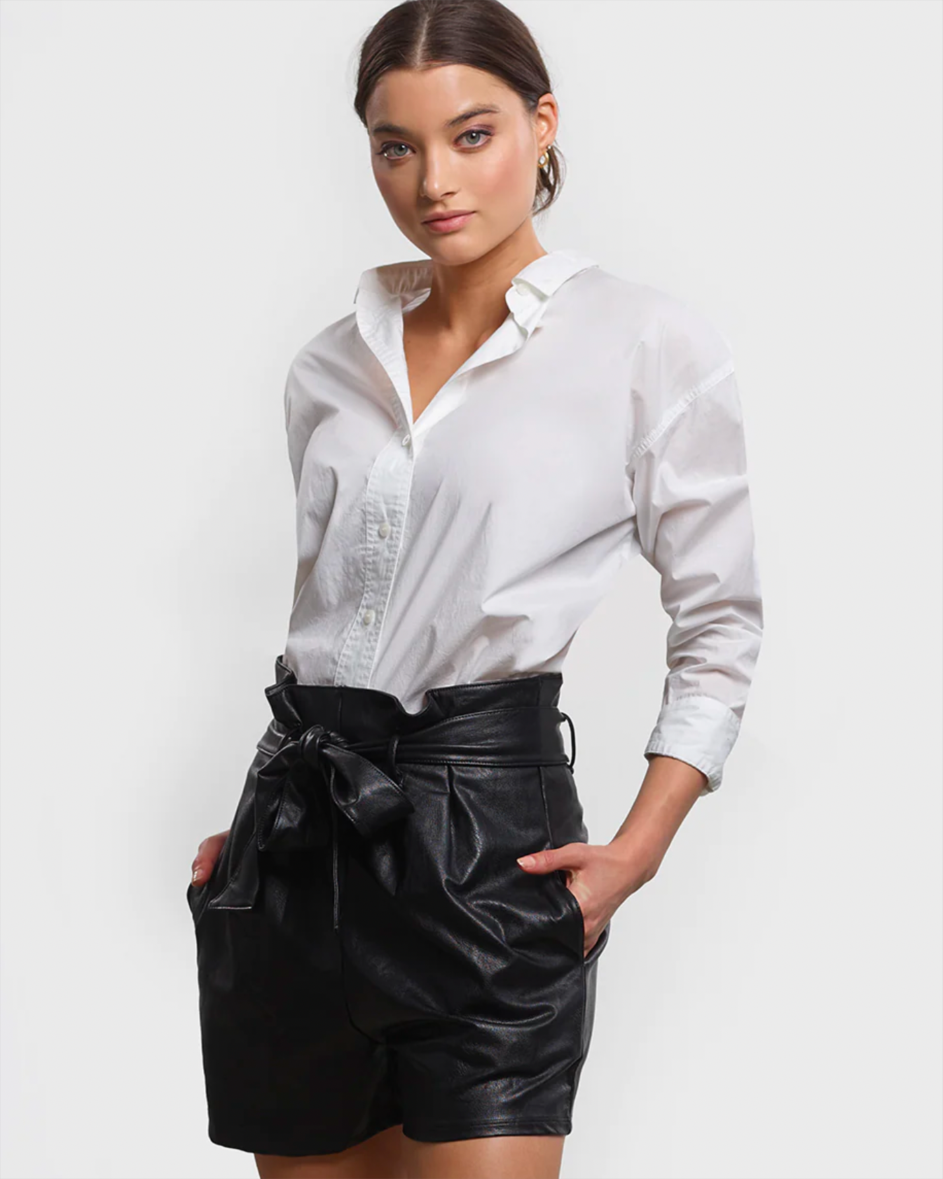 Model wearing Commando Faux Leather Paperbag Shorts in black wearing white shirt on a white background