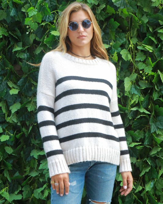 Model Wearing Wooden Ships Half Moon/Black Caroline Striped Crewneck wearing jeans and sunglasses standing in front of green vines