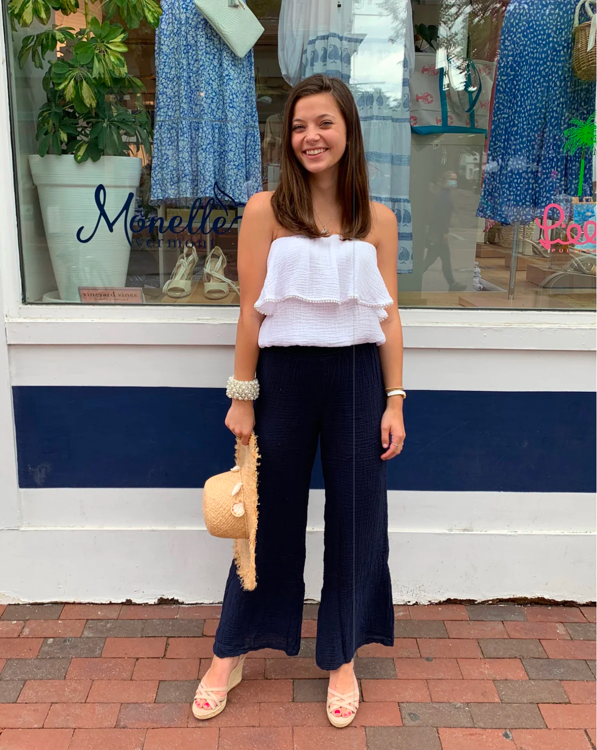 Model wearing Michael Stars Susie Smocked Waist Pant wearing white top standing in front of a clothing store window 