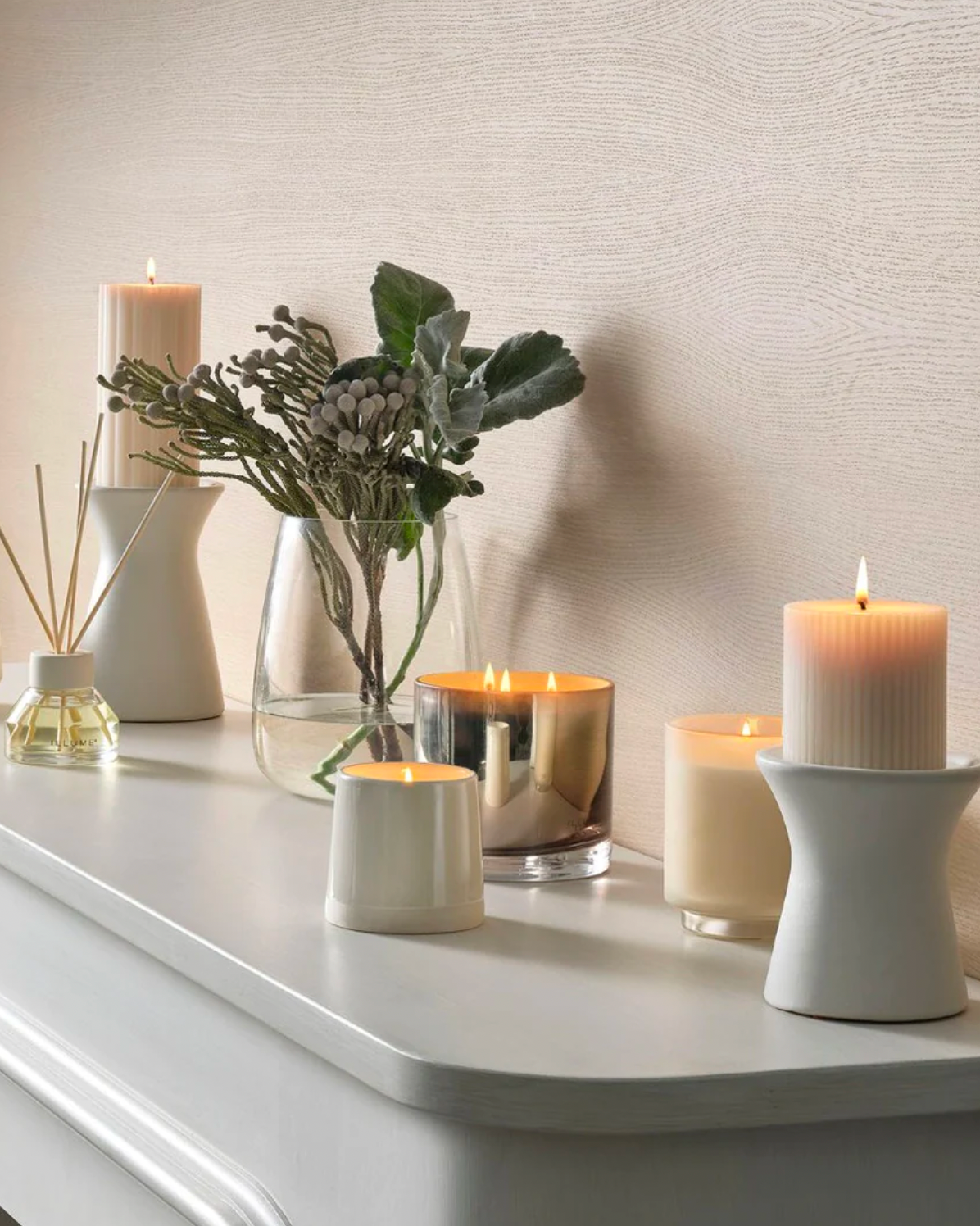 Image of ILLUME Winter white shine ceramic candle on a shelf with other candles