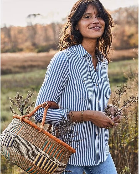 Model wearing Faherty Legend Sweater shirt in navy/white stripes wearing jeans holding a basket outside