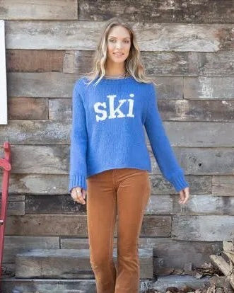 Model wearing Wooden ships SKI sweater in Aviator blue wearing brown pants on a wooden background