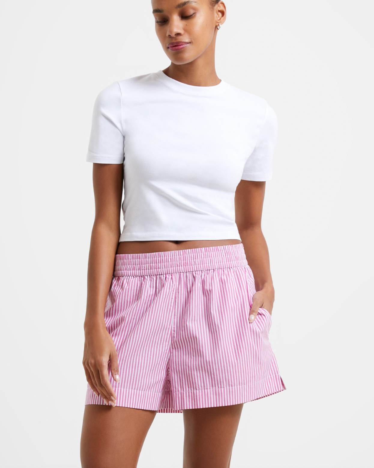 Model wearing French Connection Rhodes Poplin Stripe Shorts in wild rosa with white stripes wearing a white shirt on a white background