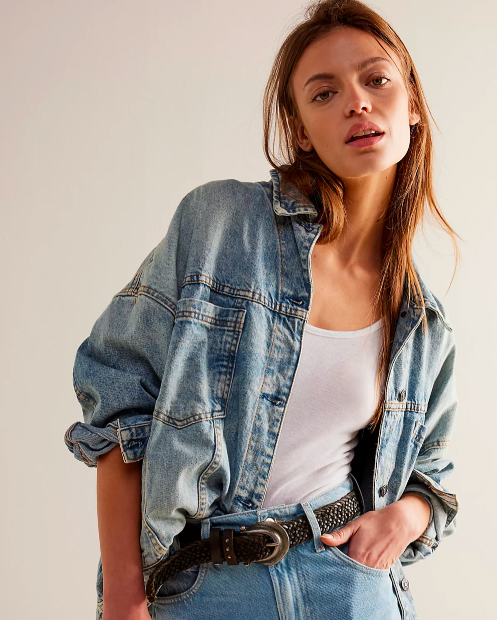 Model Wearing Free People Ocean Night Opal Swing Denim Jacket wearing Jeans and a white shirt on a white background