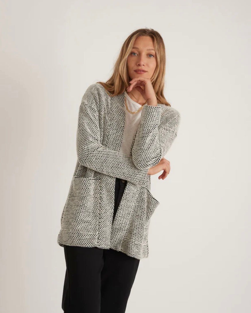 Model wearing Marine Layer Birdseye Cardigan in black and white wearing black pants on a white background