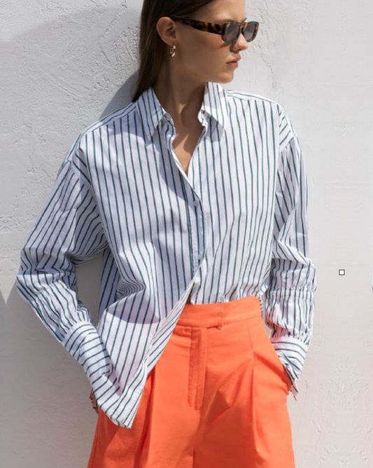 Model wearing French Connection Rhodes Poplin Button down shirt in forest green/white stripes wearing orange shorts and sunglasses on a white background