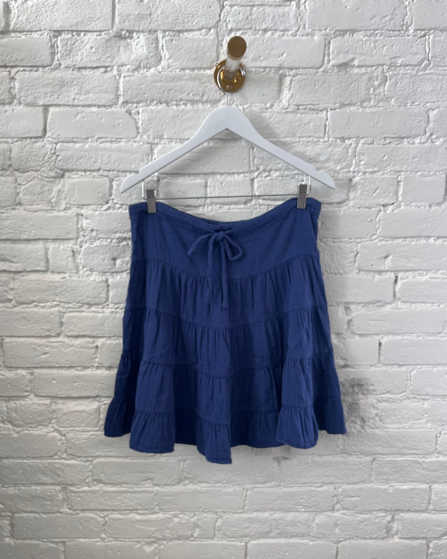 Image of Dylan Blue Gauze Sophie Skirt on a white hanger with white brick background