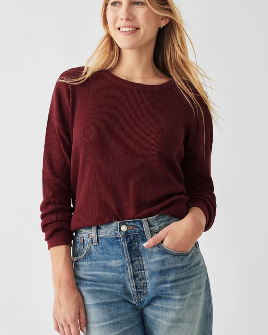 Model wearing Faherty Waffle Layering Crew long sleeve shirt in Maroon color wearing jeans on a white background